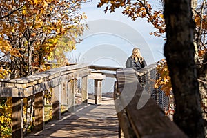 Young woman 30-35 traveler enjoys the overlook on the boardwalk at Porcupine Mountains Wilderness State Park in Michigan