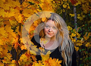 A young woman of 35 years in the autumn woods on the background of maple leaves