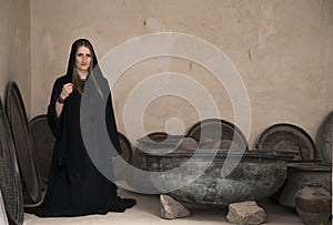 Young woman in abaya in the middle of old cooking pots