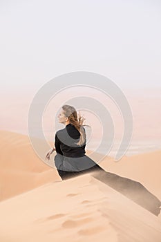 Young woman in Abaya posing in desert landscape.