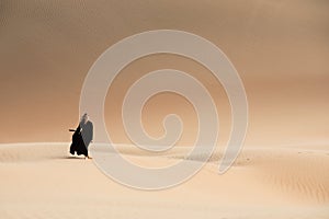 Young woman in Abaya posing in desert landscape.