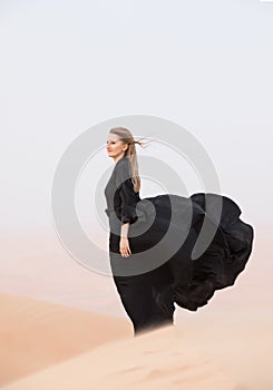 Young woman in Abaya posing in desert landscape. photo