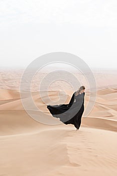 Young woman in Abaya posing in desert landscape. photo