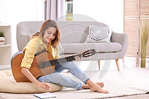 Young woman with acoustic guitar composing song photo