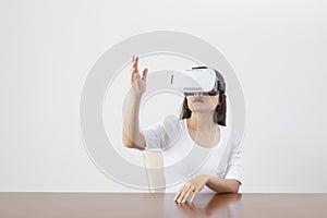 Young woman acting while wearing VR device or virtual reality glasses over white background