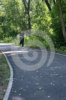 Young woman in activewear choosing healthy lifestyle. Girl runs in the park. Going to lose extra pounds. Vertical frame