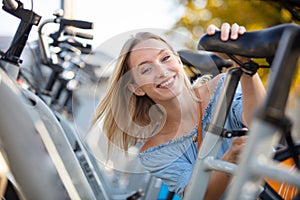 Young woman adjust seat city bike rent