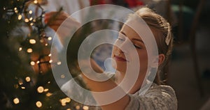 Young woman adjusting glowing led lights on tree