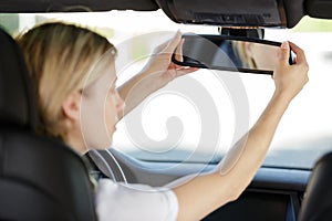 young woman adjusting rear mirror