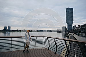 A young woman admires the views in the modern Waterfront area, near the Sava River embankment. View from the ground in a