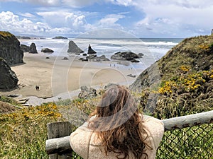 A young woman admiring the beautiful view of Bandon beach in Bandon, Oregon, with the headlands and beautiful coast