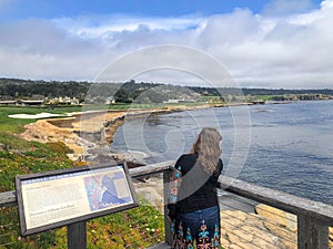 A young woman admiring the beautiful views monterey bay beside pebble beach golf course, on a beautiful spring day in California