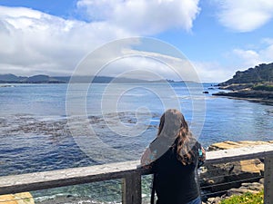 A young woman admiring the beautiful views monterey bay beside pebble beach golf course, on a beautiful spring day in California,