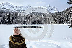 A young woman admiring the snowy views of Island Lake in Fernie, British Columbia, Canada.The majestic winter background is pretty