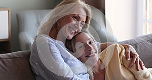 Young woman adult child nestle close to beloved aged mother