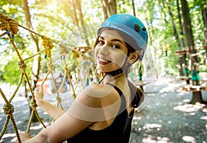 Young woman in adventure rope park. Climbing Equipment.