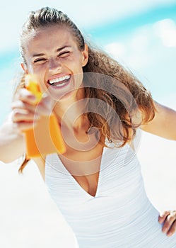 Young woman aiming bottle of sun block creme in camera