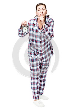 Young woman with an alarm clock in checkered pajamas showing