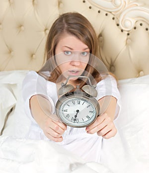 Young woman with alarmclock on the bed