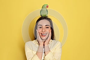 Young woman with Alexandrine parakeet on background. Cute pet