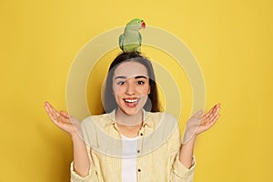 Young woman with Alexandrine parakeet on background. Cute pet