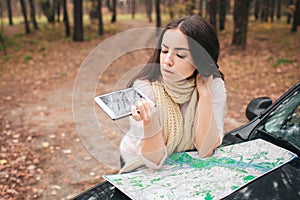 Young woman alone car traveler with map does not work gps, smartphone is broken