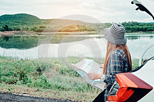 Young woman alone car traveler with map on hatchback car