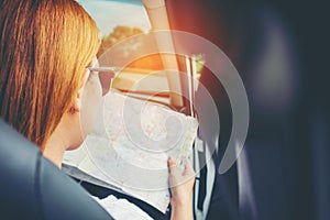 Young woman alone car traveler with map on hatchback car