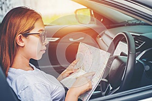 Young woman alone car traveler with map on hatchback car