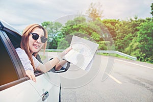 Young woman alone car traveler with map on hatchback car