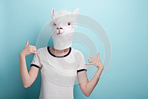 Young woman in alpaca mask with hands showing shaka sign or hang loose gesture