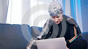 young woman with aluminum hat reacting badly on the conspiracy theory post about 5g microwaves and covid-19 connection