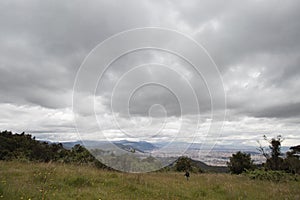 young woman into an andean countryside landscape with grey clouds and bogota city