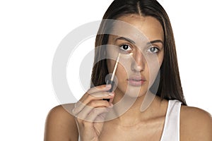 A young woman applies concealer under her eyes