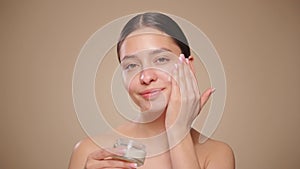 Young woman applies skin care cream to her face