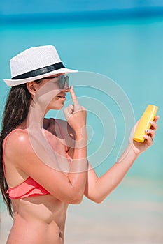 Young woman apply cream on her nose at beach