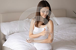 Young woman apply nourishing body cream on arm