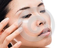 Young woman applying anti-wrinkles eye moisturizer