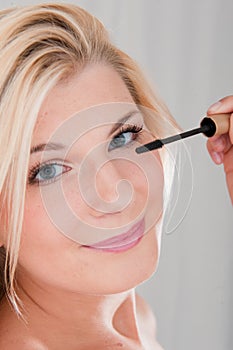 Young woman applying black eye mascara