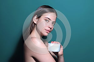 Young woman applying body cream against studio background. Beauty routine. Studio face of a beautiful woman with perfect
