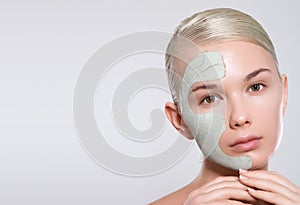 Young woman applying clay face mask and having fun. Daily morning routine - facial cleaning, skin care