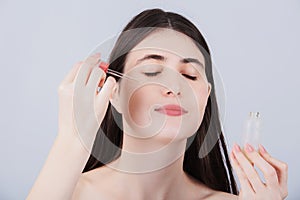 Young  woman applying cosmetic facial oil on face with pipette.Natural organic cosmetic product for skin care and skin