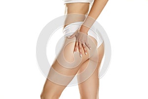 Young woman applying cream on her buttocks