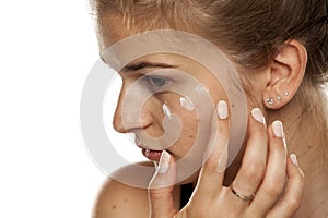 Young woman applying cream on her face