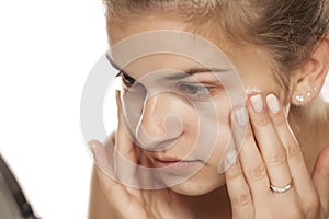 Young woman applying cream on her face