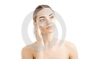 Young woman applying cream onto her face