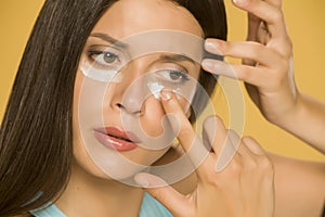 Young woman applying a creme on her  low eyelids