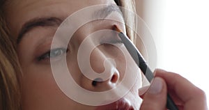 Young woman applying eyeshadows, looking at mirror