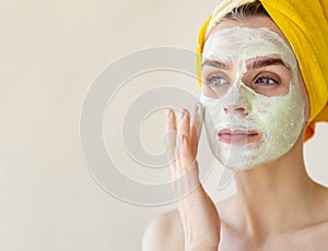 Young woman applying facial clay green mask. Beauty treatments concept with copy space. Close Up portrait