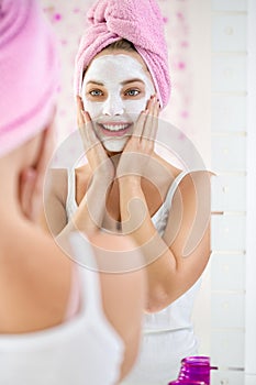 Young woman applying facial cleansing mask